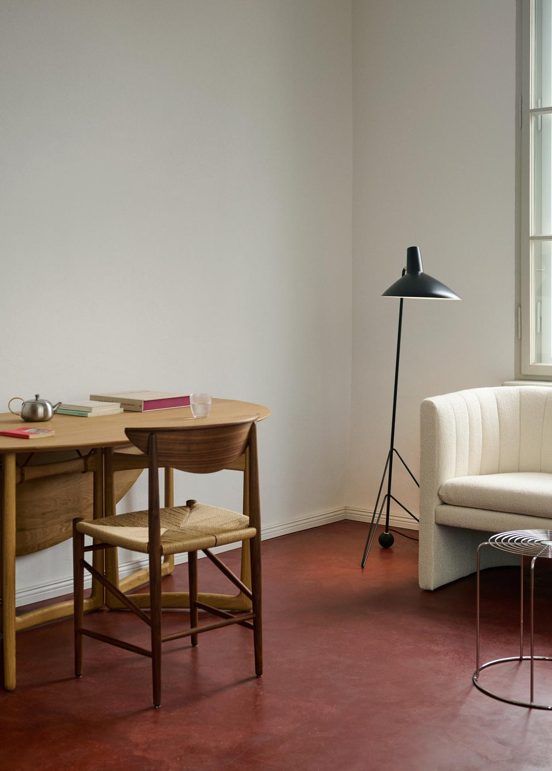 Skrivbord och stol i trä med en svart lampa och vit soffa