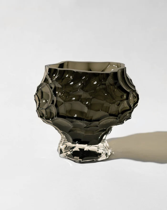 En unikt formad svart vas framför en vit bakgrund