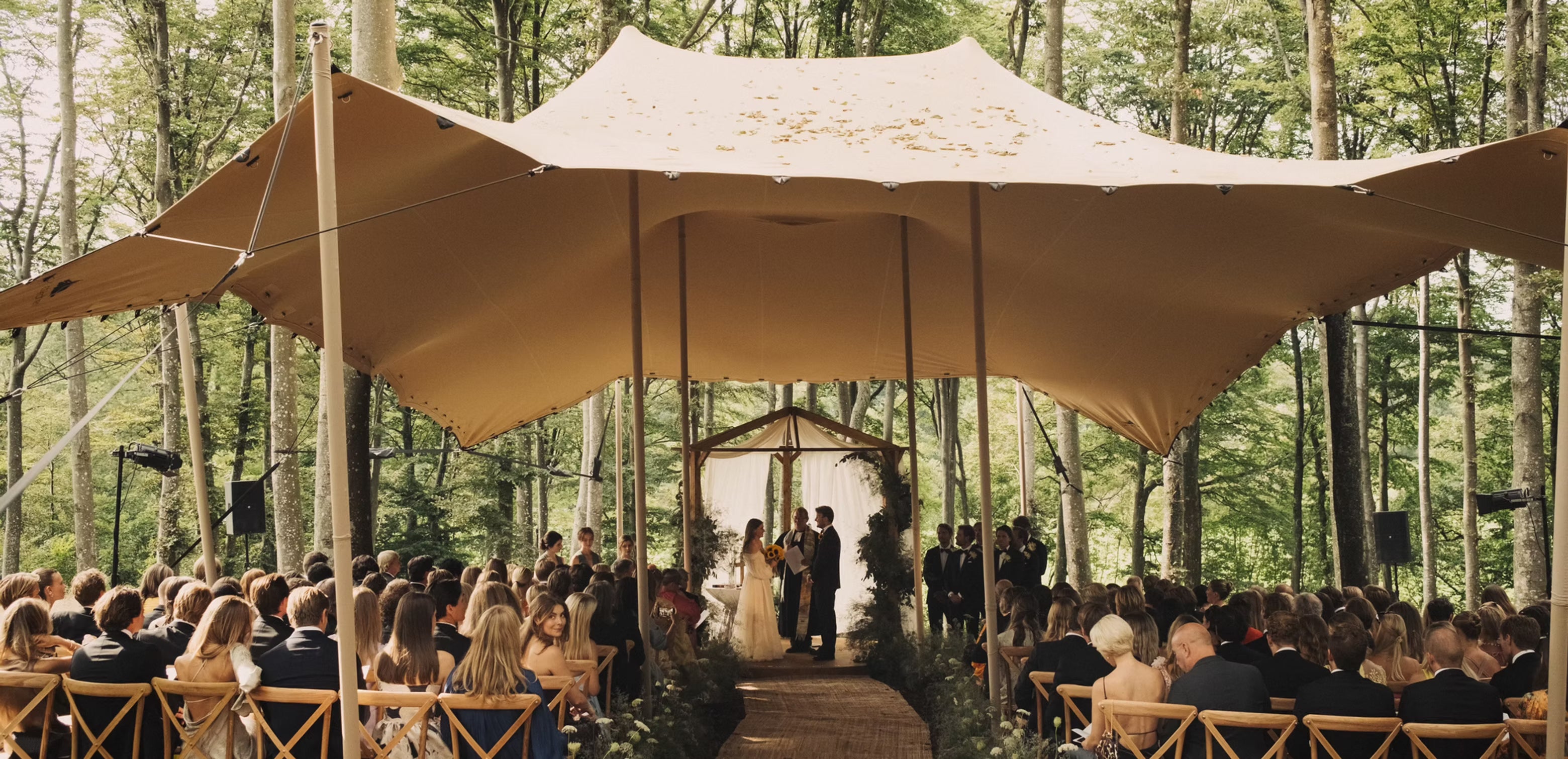 En vacker bröllopsbild under en tältduk i skogen