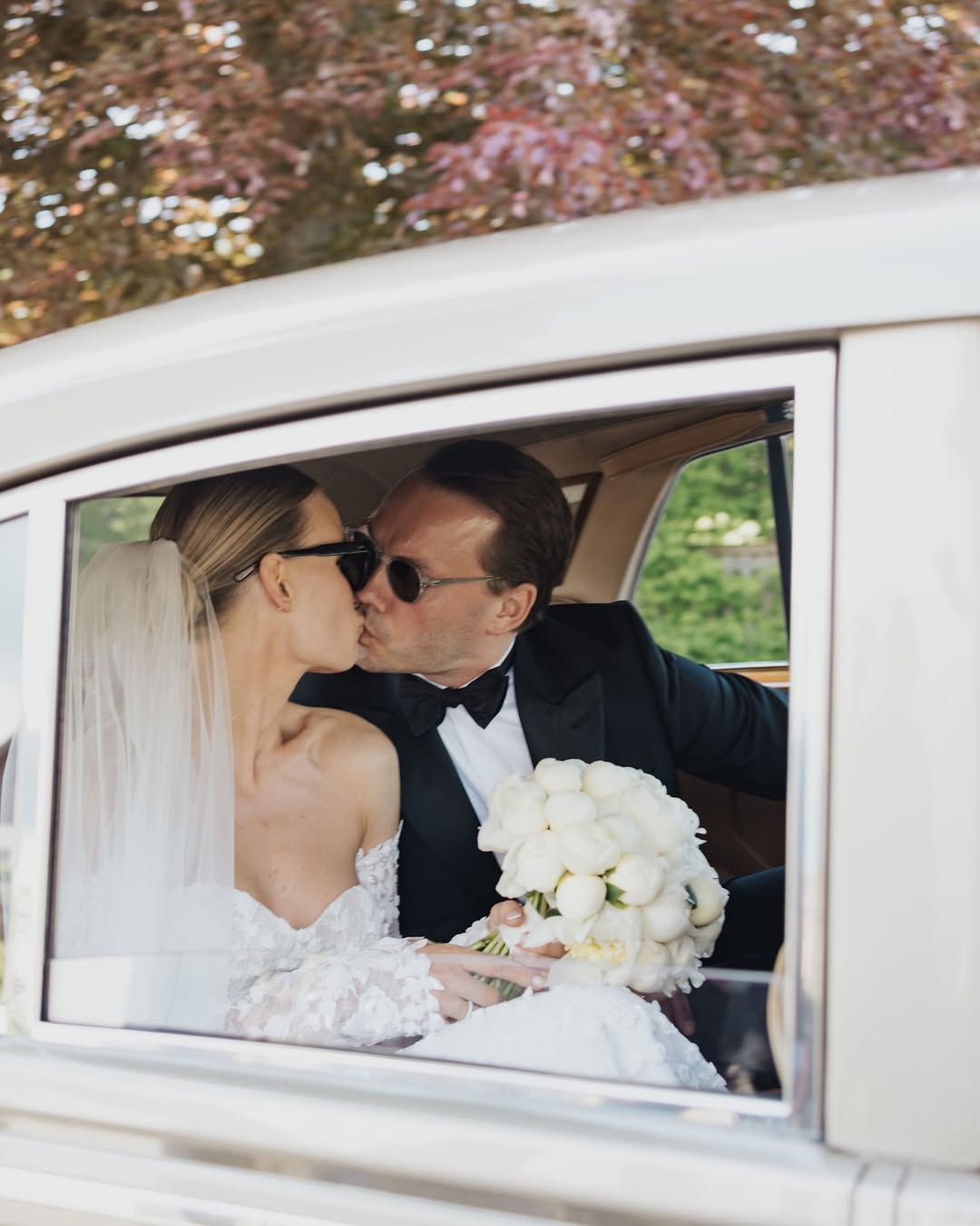 Bröllopsbild på ett brudpar genom fönsterrutan på en bil