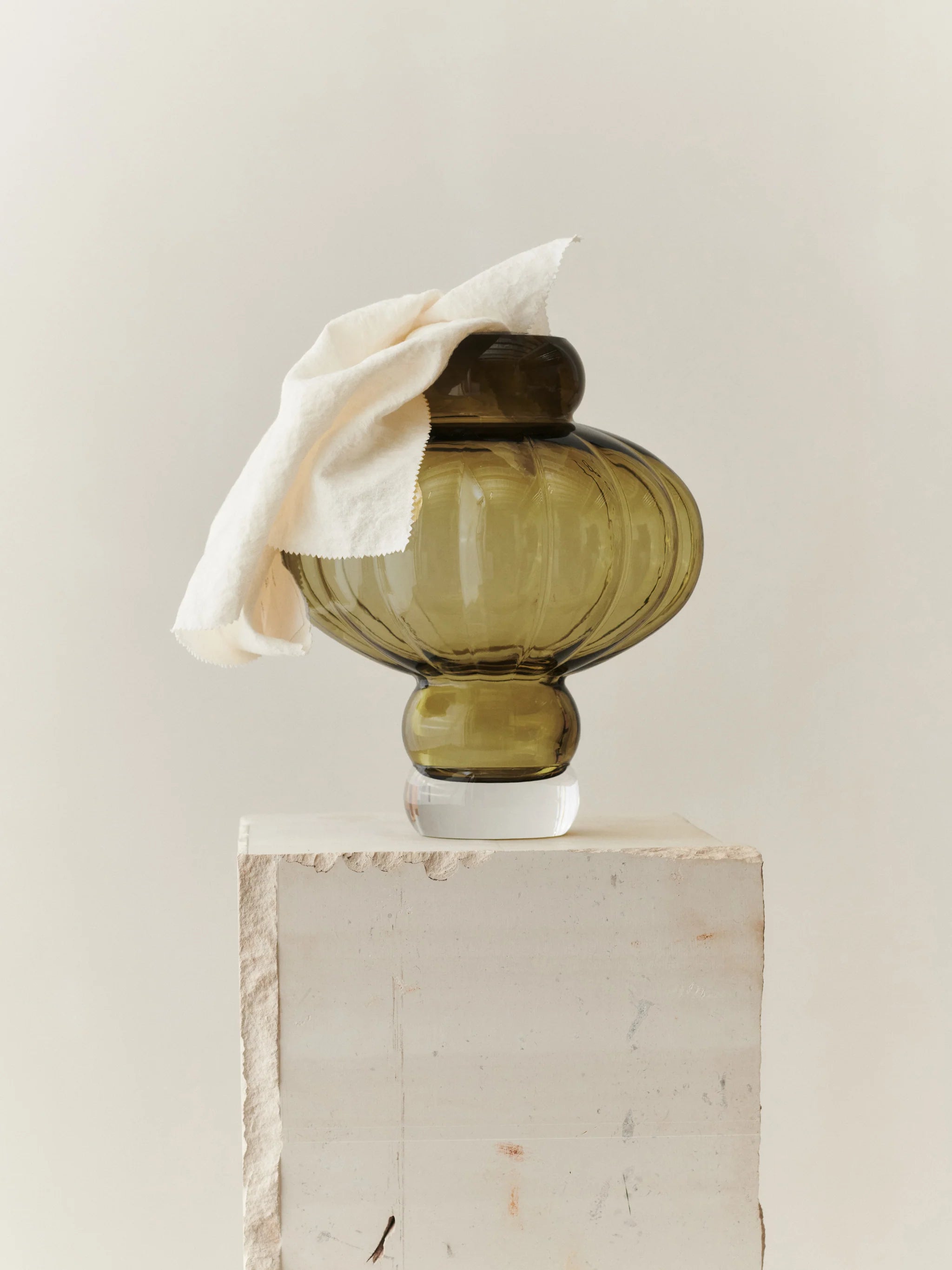 En vacker formad grön vas på ett vitt bord