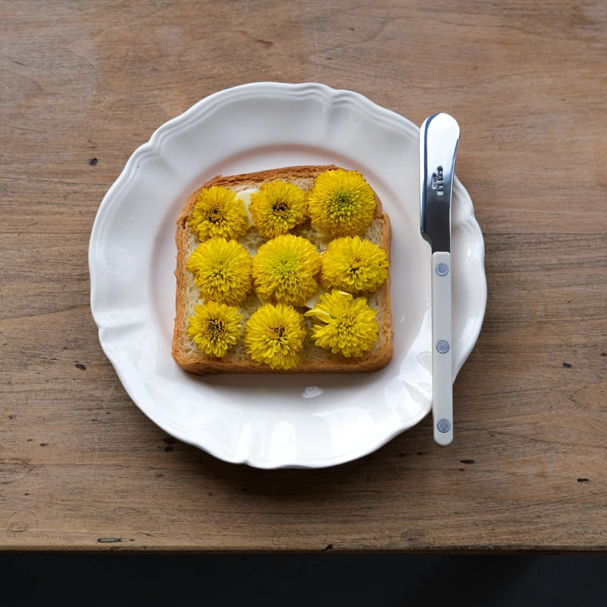 Vit tallrik med bröd med blommor på, vacker tallrik och bestick